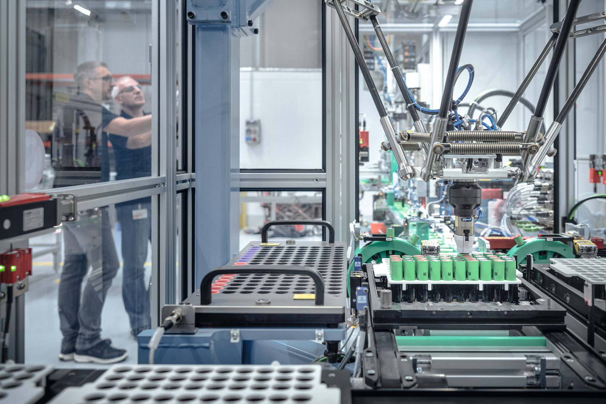 Двоє чоловіків на виробництві акумуляторів в оточенні роботів та верстатів