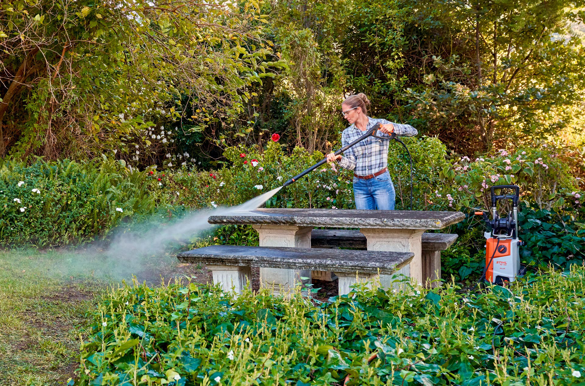 Frau bei der Außenreinigung ihrer Gartenmöbel mit einem STIHL Hochdruckreiniger