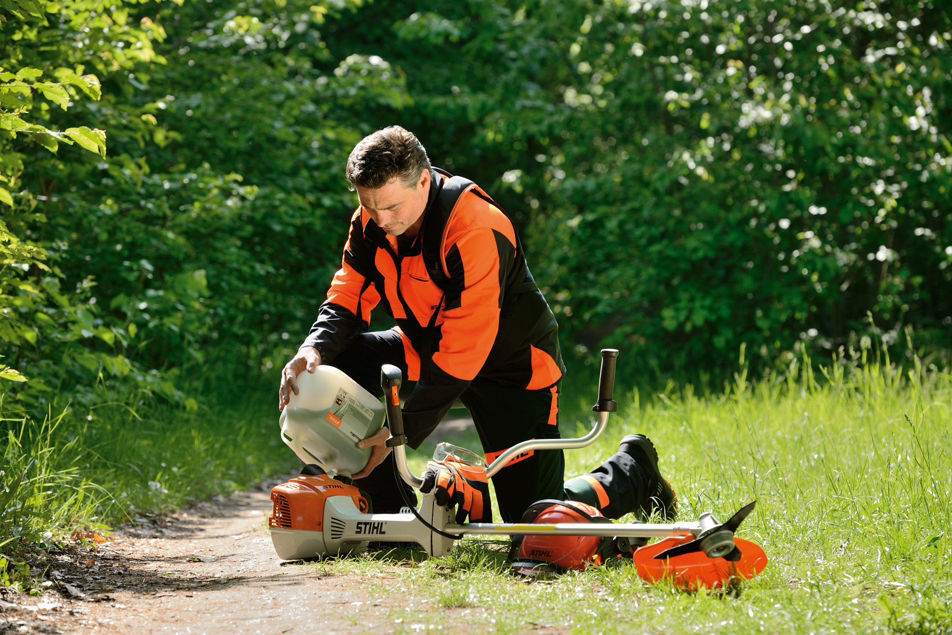 Чоловік заправляє мотокосу STIHL бензиново-мастильною сумішшю