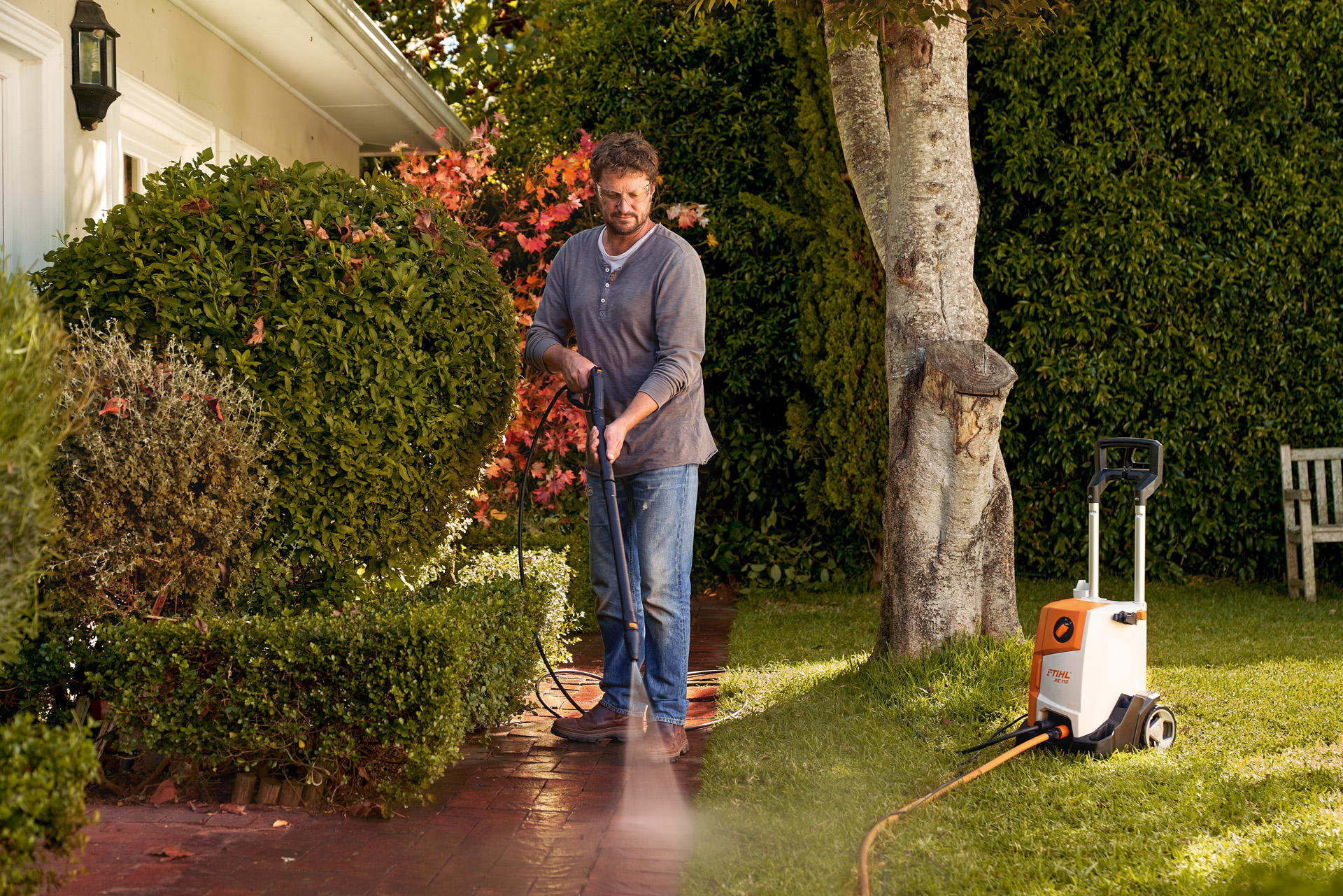 Mann reinigt Pflastersteine vor seinem Haus mit STIHL Hochdruckreiniger RE 110