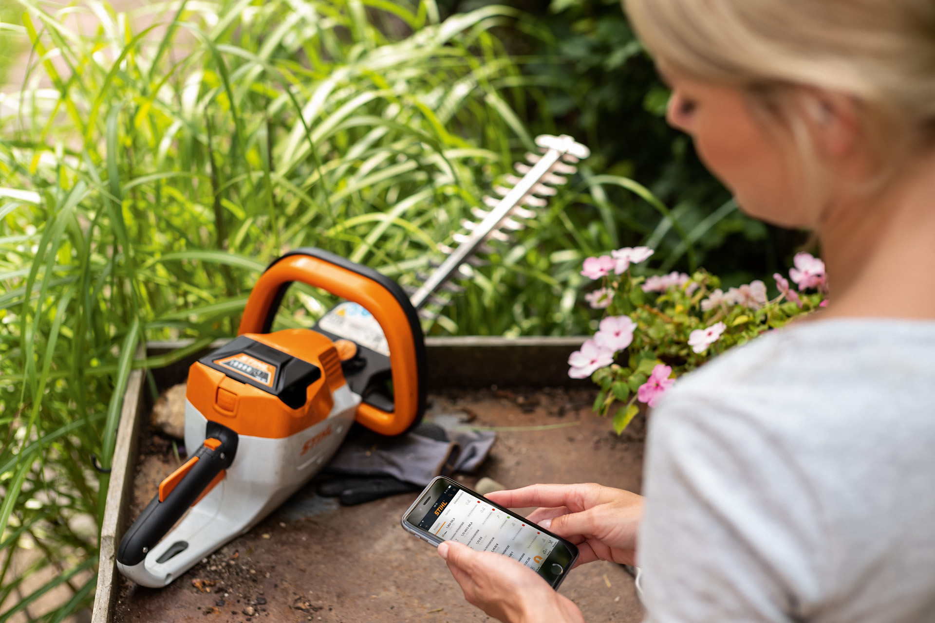 Жінка реєструє мотоножиці STIHL за допомогою додатку STIHL на смартфоні