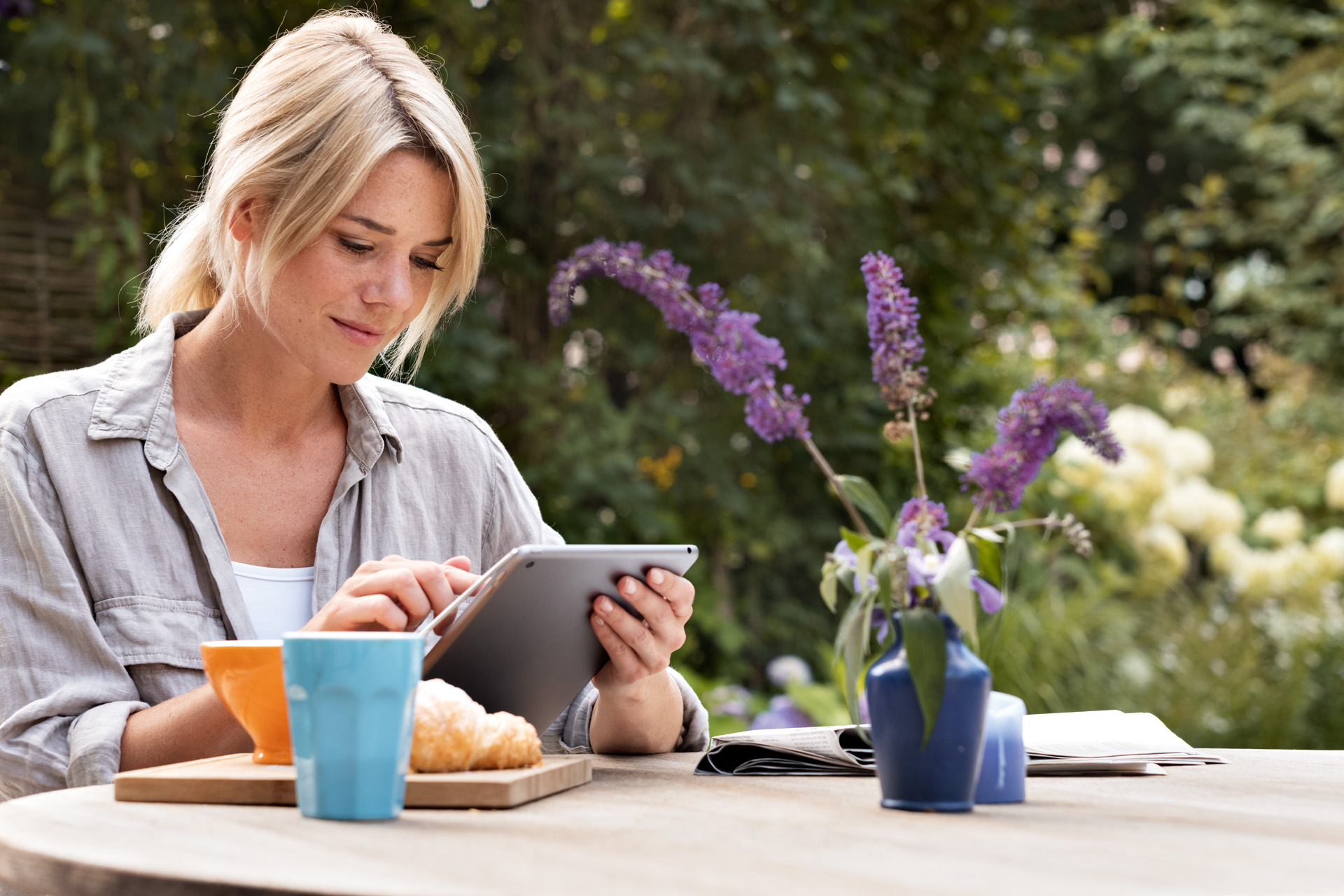 Жінка користується планшетом за сніданком у саду